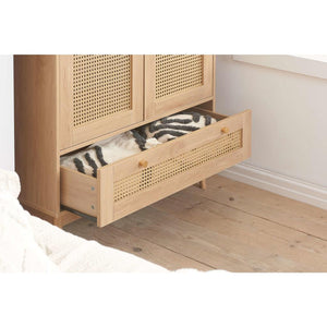 Wooden wardrobe with open drawer containing striped fabric on a wooden floor.