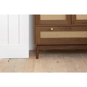 Wooden wardrobe with rattan detailing on a wooden floor.