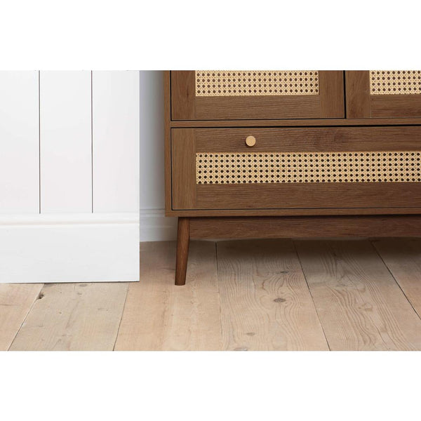 Wooden wardrobe with rattan detailing on a wooden floor.