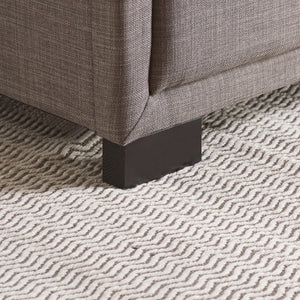 Close-up of a textured gray fabric surface with a patterned rug underneath.