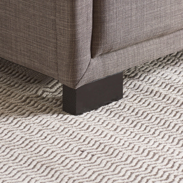 Close-up of a textured gray fabric surface with a patterned rug underneath.