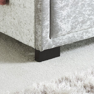 Close-up of a upholstered bed frame with a black foot.