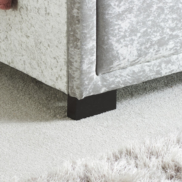 Close-up of a upholstered bed frame with a black foot.
