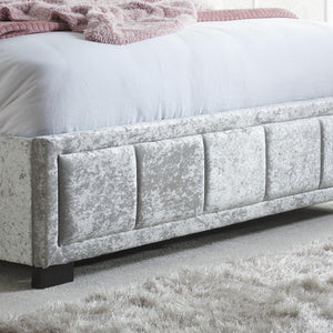 Gray upholstered bed with a textured finish on a light gray carpet.