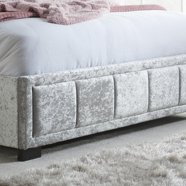 Gray upholstered bed with a textured finish on a light gray carpet.