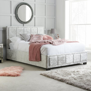 Neatly made bed with pink throw blanket in a bedroom setting.