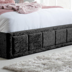 Black crushed velvet bed with white bedding and pink blanket in a bedroom setting