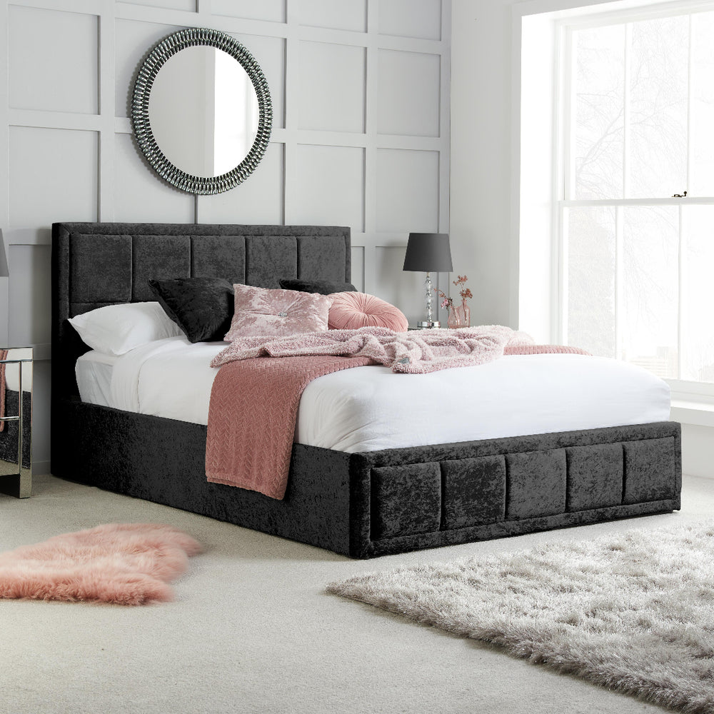 Black upholstered bed with white bedding on a white background
