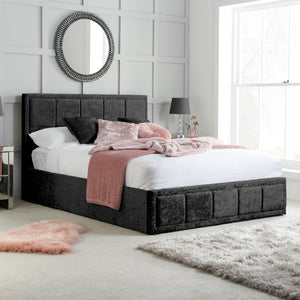 Gray upholstered bed with white bedding and pink accents in a bedroom setting.