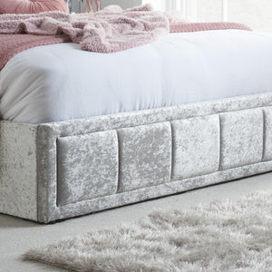 Gray upholstered bed with pink bedding in a bedroom setting