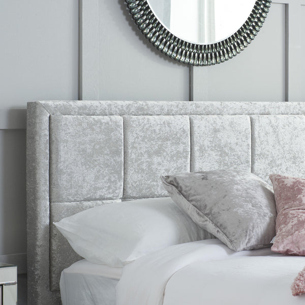 Gray upholstered headboard with decorative pillows in a bedroom setting.
