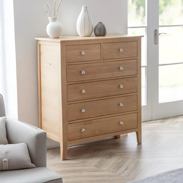 Wooden dresser with silver knobs in a room with a light gray sofa and white walls.