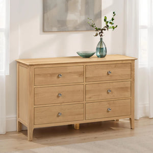 Wooden dresser with six drawers in a room setting.