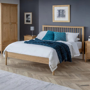 Bedroom with wooden bed frame, nightstands, and framed pictures on a gray wall.
