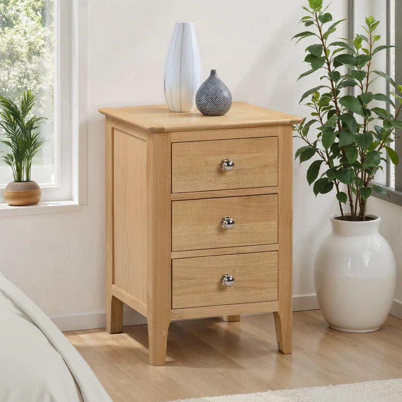 Wooden nightstand with three drawers on a white background