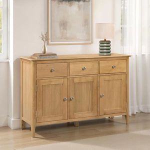 Wooden sideboard with drawers and doors in a room with a mirror and lamp.