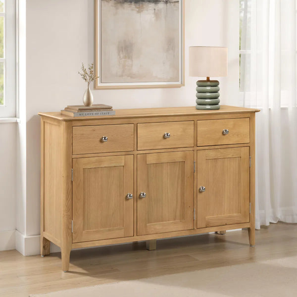 Wooden sideboard with drawers and doors in a room with a mirror and lamp.