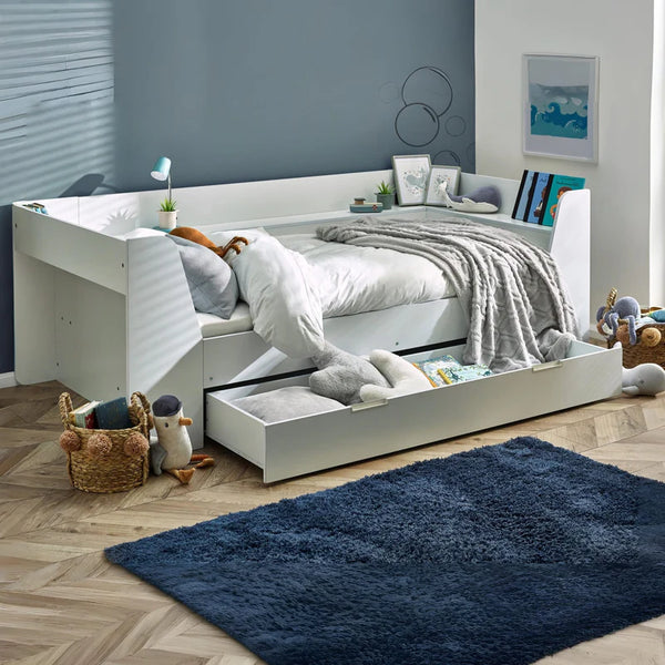 White bed with storage drawers in a room with a blue rug and toys.