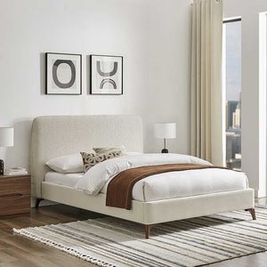Beige upholstered bed in a modern bedroom with abstract art on the wall.