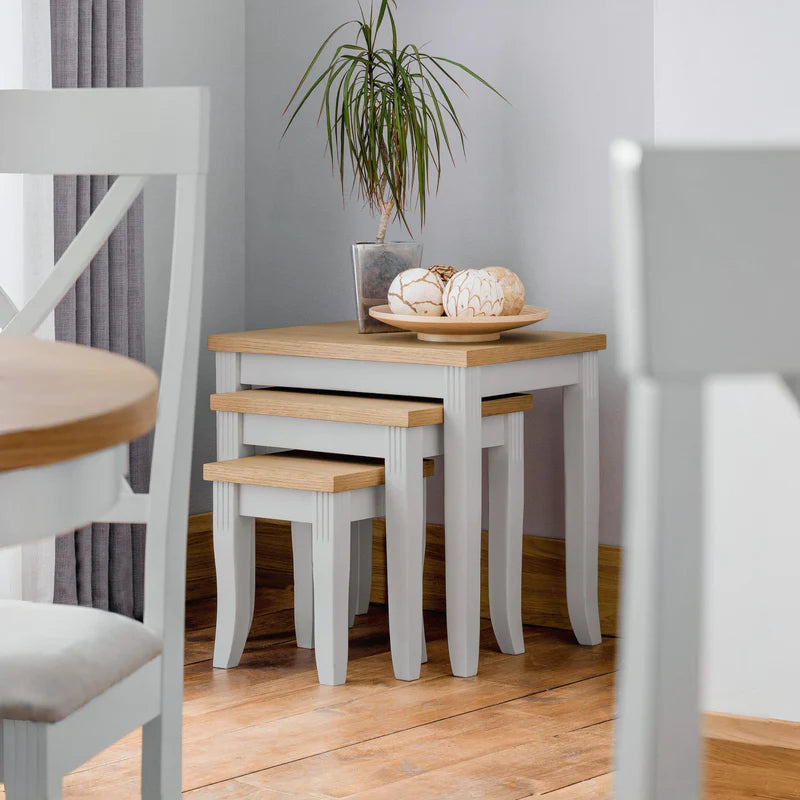 Set of three nesting tables with wooden tops and white bases on a white background