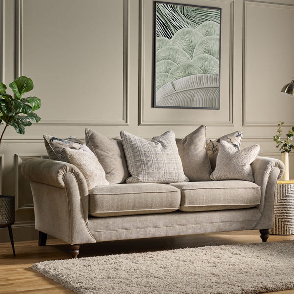 Living room with beige sofa and armchair, framed artwork on the wall, and a lamp.