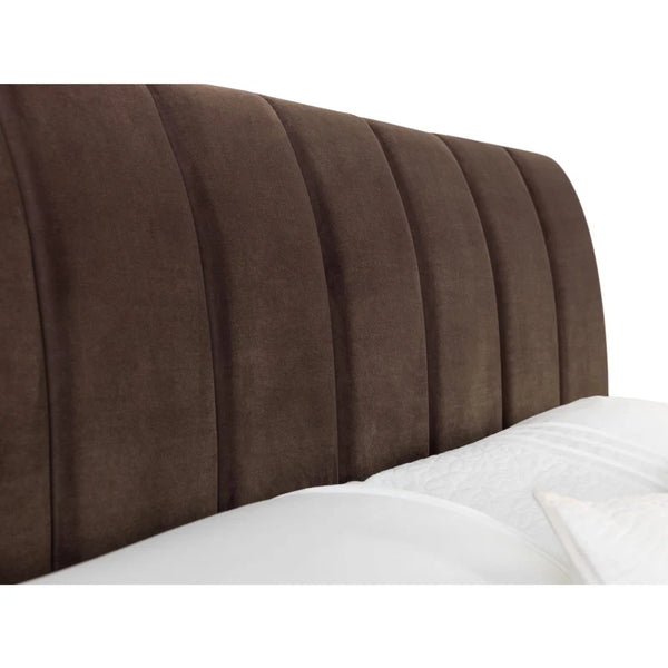 Brown upholstered headboard on a bed with white bedding
