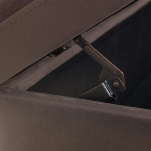 Close-up of a brown fabric ottoman with a metal handle.