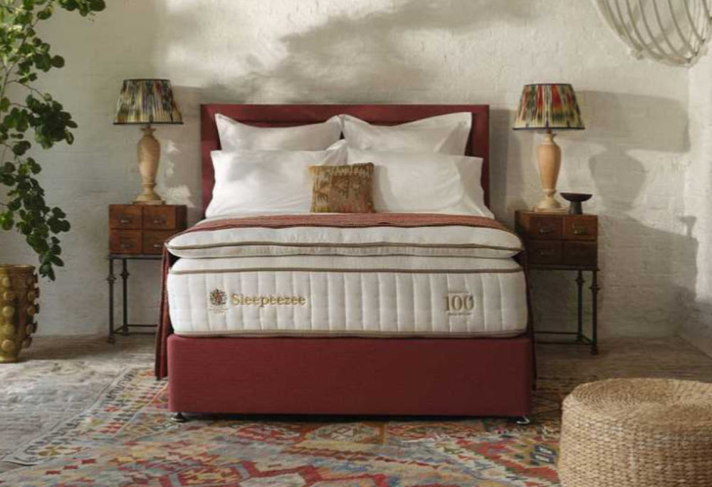 Sleepeezee Bed with red headboard and white bedding in a room with lamps and decor.