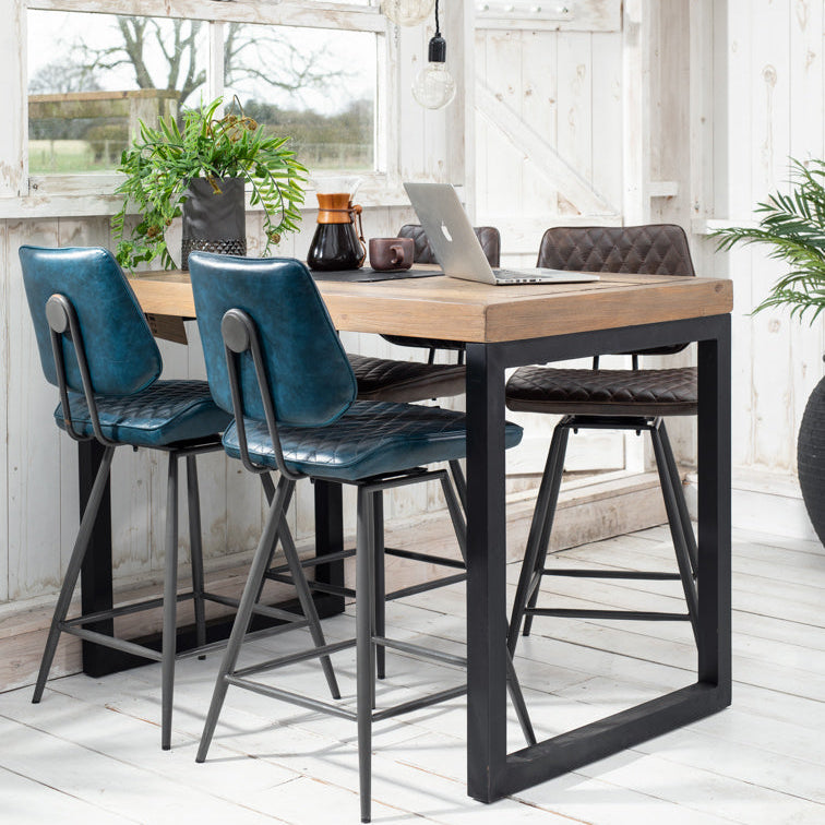 Black quilted bar stool in a modern room with wooden furniture and large windows.