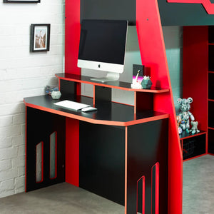 Black and red computer desk with a monitor, keyboard, and mouse in a room with a white brick wall.