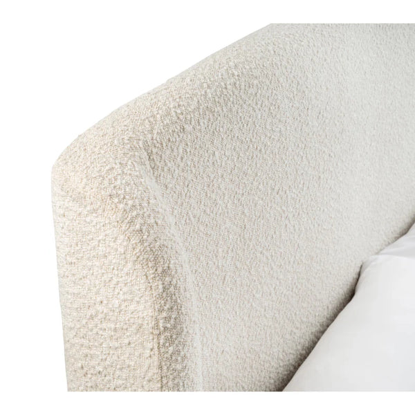 Close-up of a textured beige armchair corner with a white pillow.