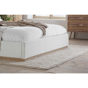 White upholstered bed with wooden frame in a bedroom setting