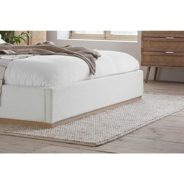 White upholstered bed with wooden frame in a bedroom setting