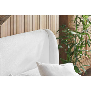 White upholstered headboard with a plant in the corner
