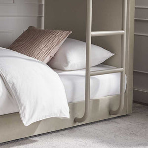 Beige bunk bed with white bedding and a brown textured pillow against a neutral wall.