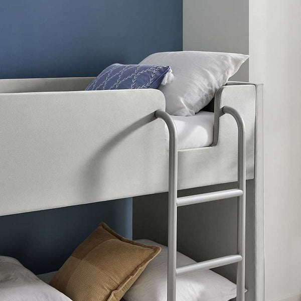 Bunk bed with white mattress and gray metal ladder against a blue wall.