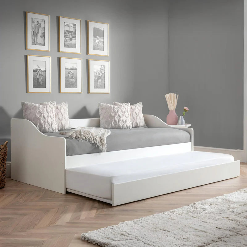White bed with a purple mattress and decorative pillows on a white background