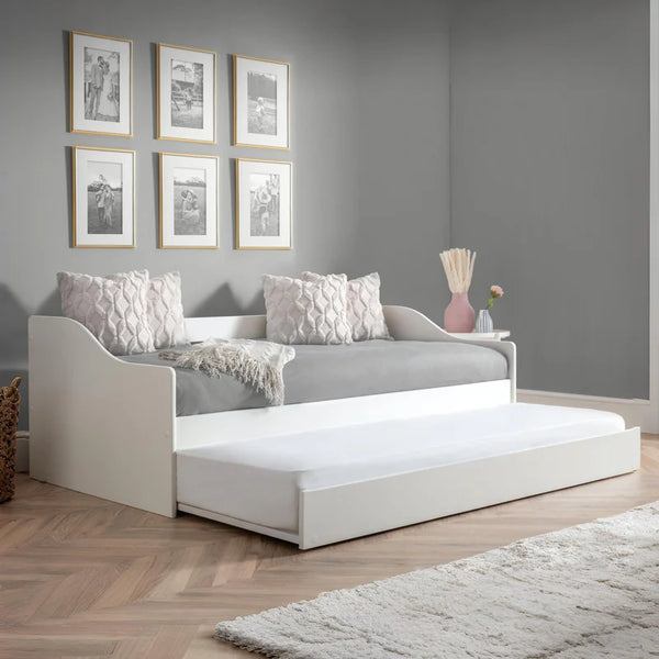 White daybed with pull-out trundle in a room with gray walls and wooden flooring.