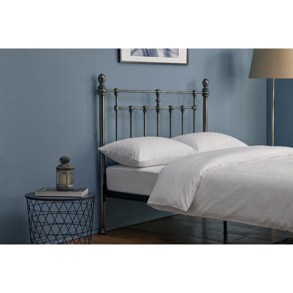 Bedroom with a metal bed frame, white bedding, and a side table with a lantern.