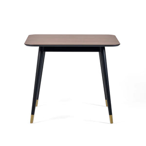 Square table with wooden top and black legs with gold accents on a white background