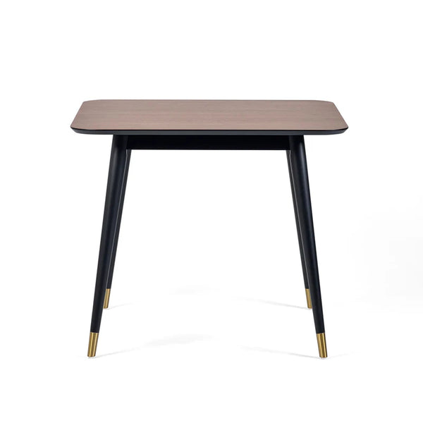 Square table with wooden top and black legs with gold accents on a white background