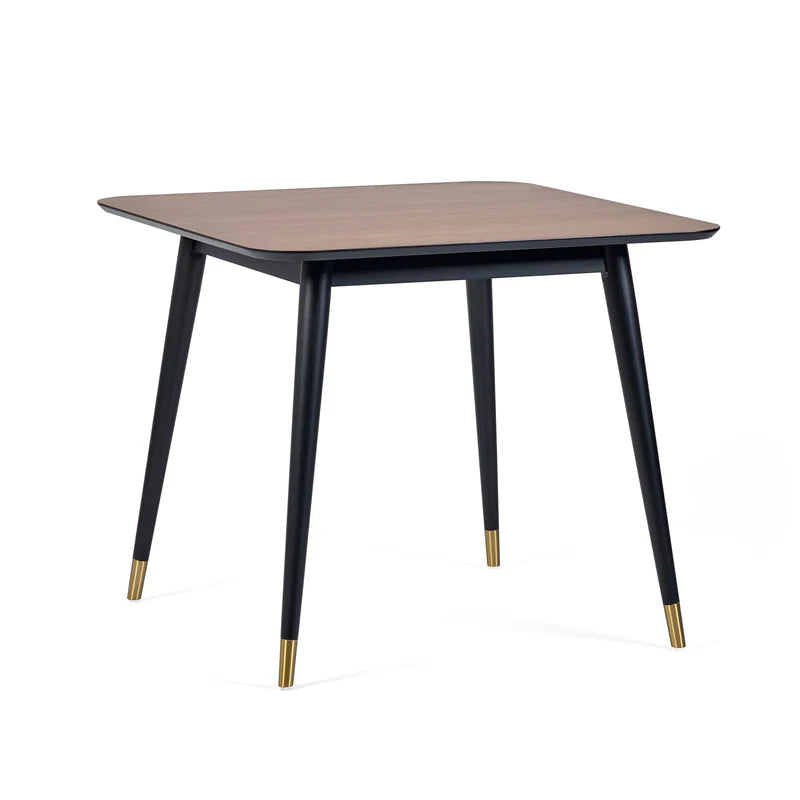 Square table with wooden top and black legs with gold accents on a white background
