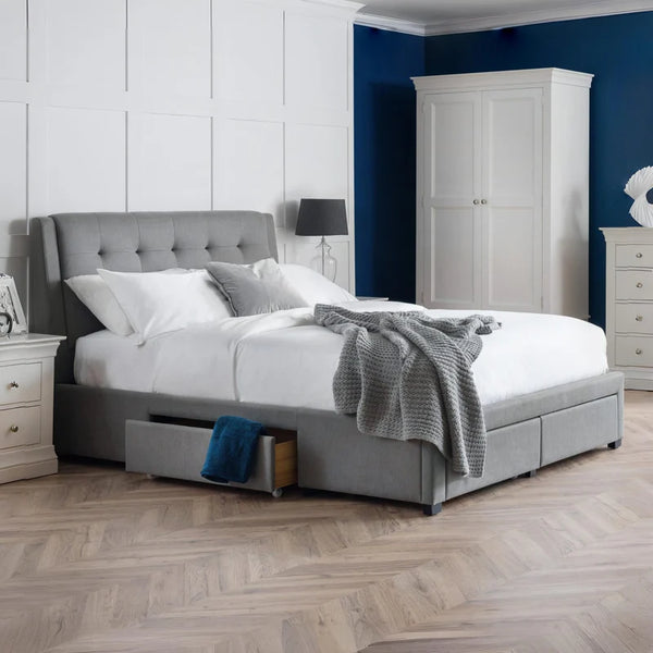 Gray upholstered bed with white bedding in a bedroom setting.