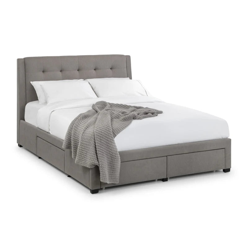 Gray upholstered bed with white bedding and a gray blanket on a white background