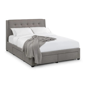 Gray upholstered bed with white bedding and a gray blanket on a white background