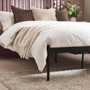 Bed with beige bedding and pillows in a bedroom setting
