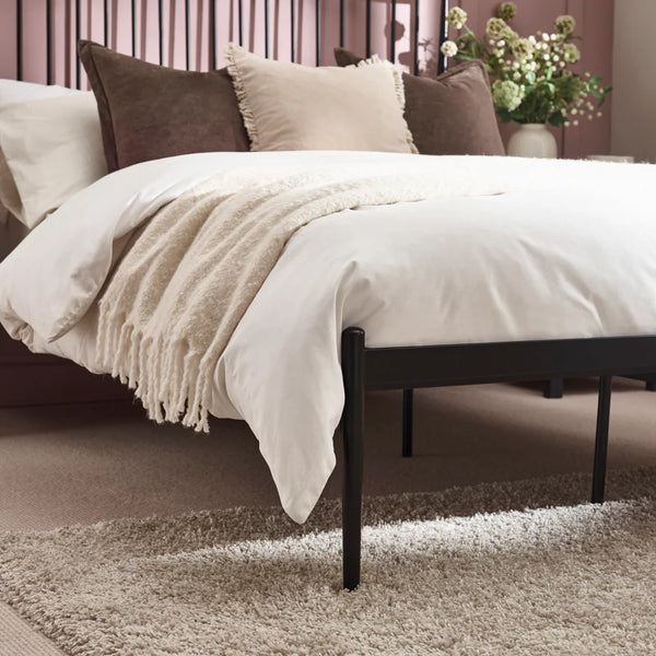 Bed with beige bedding and pillows in a bedroom setting