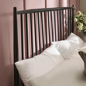 Bed with black metal headboard and white bedding against a striped wall.
