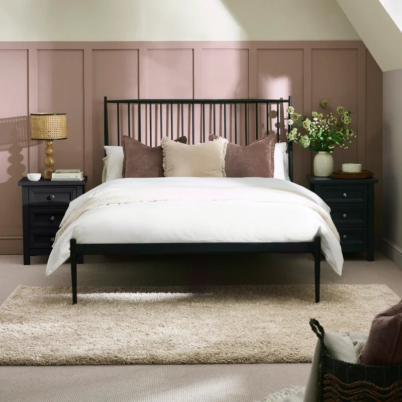 Black metal bed frame with white bedding on a white background