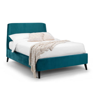 Teal bed with white bedding and beige blanket on a white background